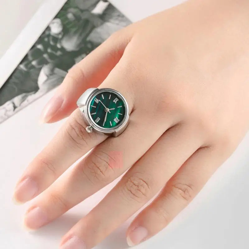 Silver and green punk finger watch displayed on finger